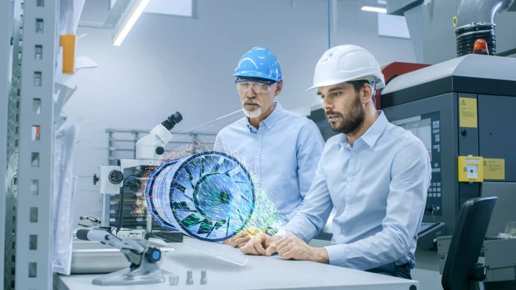 Zwei Männer mit Helmen vor Mikroskop in digitaler, moderner Fertigungshalle