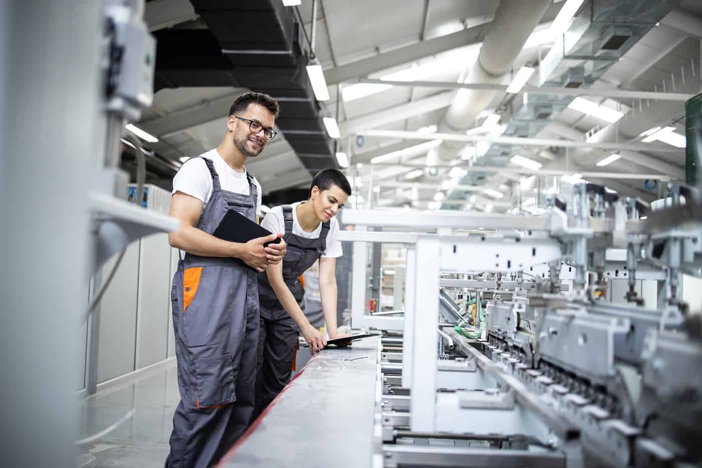 Produktionsmitarbeiter, die den Herstellungsprozess moderner Verpackungsindustriemaschinen in der Druckerei kontrollieren.